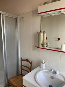 bagno con lavandino, specchio e sedia di Les Hirondelles de la villa des roses a Pontmain