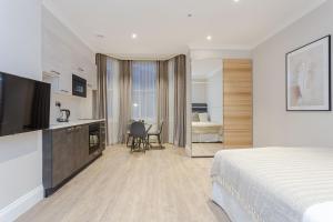 a hotel room with a bed and a kitchen and a bathroom at Cleveland Residences Chelsea in London