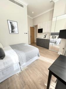 a white bedroom with a bed and a table at Cleveland Residences Chelsea in London
