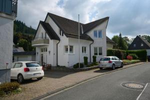 dos autos estacionados frente a una casa blanca en Ferienhaus Schulte - Villa Jupp und Apartment Liesl, en Olsberg
