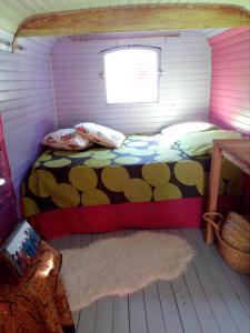 a small bedroom with a bed in a room at Roulotte Tzigane au bord du ruisseau - Drôme Provençale (2p) in Marsanne