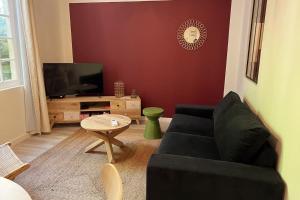 a living room with a black couch and a table at LE FIGUIER - CLIM - WIFI in Villeneuve-lès-Avignon