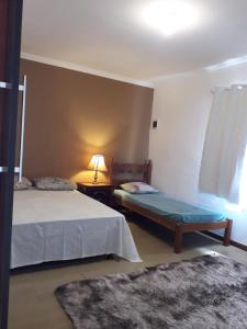 a bedroom with two beds and a lamp and a rug at Casa Super CONFORTÁVEL a 8min da praia do Forte in Cabo Frio