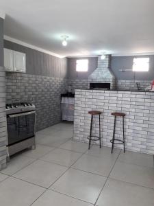a kitchen with two bar stools and a stove at Casa Super CONFORTÁVEL a 8min da praia do Forte in Cabo Frio