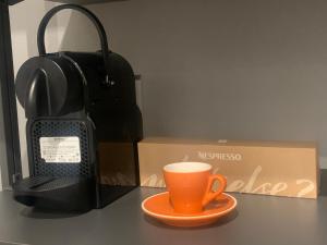 una tazza di caffè arancione seduta su un tavolo accanto a una scatola di Rivacentro 2 a Riva del Garda