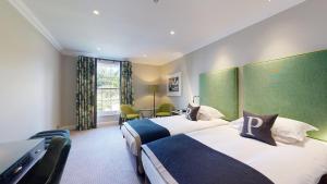 um quarto de hotel com duas camas e uma secretária em Rudding Park em Harrogate