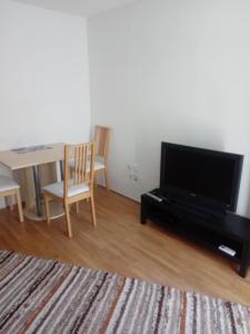 a living room with a tv and a table with chairs at V klancu in Dekani