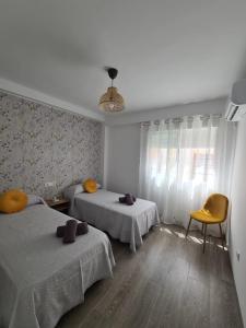 a bedroom with two beds and a yellow chair at COLON Nerja in Nerja