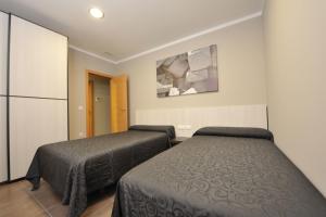 a bedroom with two beds and a painting on the wall at Aparthotel Meseguer in Alcañiz