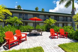 a patio with chairs and a table and an umbrella at Room 127 - Waterfront, Heated Pool, Huge TV, Tiki Bar & Grill in Sarasota