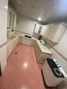 麥地那的住宿－شقق منازل طيبة，厨房配有粉红色的瓷砖地板和白色的橱柜