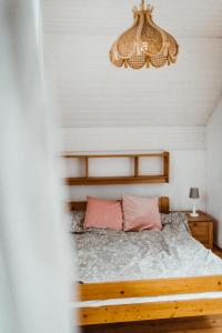 a bedroom with a bed with pink pillows and a chandelier at Konkelówka- Dom z ogrodem i sauną, Góra Żar i jezioro in Międzybrodzie Żywieckie