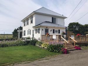 Cape Tormentine的住宿－The Coastal Country House in New Brunswick，白色的房子,带门廊和一些鲜花