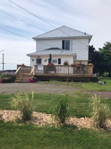 a white house with a porch and a deck at The Coastal Country House in New Brunswick in Cape Tormentine