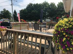 a deck with chairs and an umbrella and flowers at The Coastal Country House in New Brunswick in Cape Tormentine