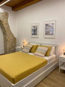 a bedroom with a large bed with yellow sheets at All’ombra del campanile in Tarquinia