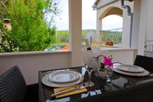 a table with plates and glasses on a balcony at Apartments by the sea Molat - 18433 in Molat +15 photos
