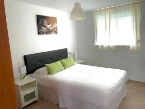 1 dormitorio con 1 cama con sábanas blancas y almohadas verdes en APARTAMENTO PLAYA DE ESTORDE, en Cee