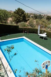 uma piscina azul com uma mesa e um baloiço em Casa rural Balcón de Monachil em Monachil