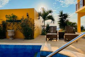 Casa amarilla con 2 sillas y piscina en Beso del Sol, en Santa Marianita
