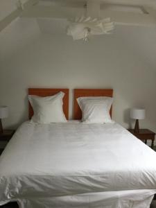 a large white bed with two pillows and a ceiling at LA MABONNAIS in Pleurtuit