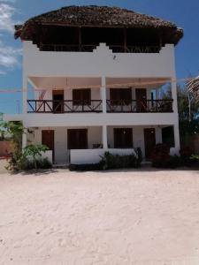 a white building with a balcony on the beach at New Arisen Bungalows in Bwejuu