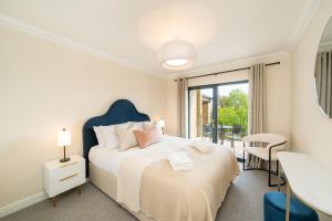 a white bedroom with a bed and a balcony at At The Castle in Broughty Ferry