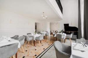 a restaurant with white tables and chairs and a piano at IBB Hotel Grand Hotel Lublin in Lublin