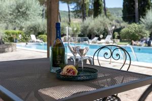uma garrafa de vinho e copos numa mesa em Dolce Far Niente Apartment with pool & parking em Passignano sul Trasimeno