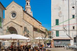 un vecchio edificio con torre dell'orologio e tavoli e ombrelloni di CasaBaltó a Sanremo