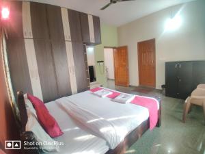 1 dormitorio con 1 cama con sábanas blancas y almohadas rojas en Nandana Home stay, en Mysore