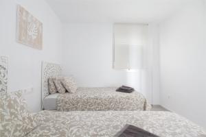 um quarto branco com uma cama e uma cadeira em Sunset Beach II em Santa Pola