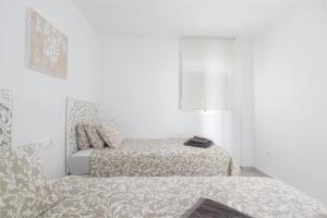una habitación blanca con una cama y una silla en Sunset Beach II, en Santa Pola