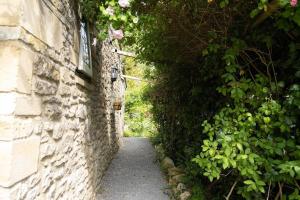 uma parede de pedra com um caminho estreito ao lado de um edifício em Lovely property in the heart of Somerset, sleeps 9 em Shepton Mallet