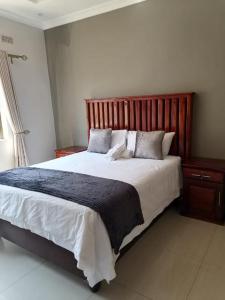 Schlafzimmer mit einem großen Bett mit einem Kopfteil aus Holz in der Unterkunft 848 Guest House in Victoriafälle