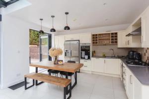 a kitchen with white cabinets and a wooden table at Luxury 2 Bedroom Apartment with gym in London