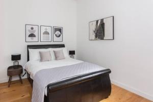 a bedroom with a bed with white sheets and pictures at Luxury 2 Bedroom Apartment with gym in London