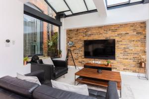 a living room with a brick wall and a tv at Luxury 2 Bedroom Apartment with gym in London