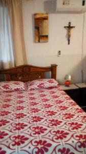 a bedroom with a red and white bed with a cross on the wall at Green Sea Villa Helen Inn, Kilometer 4 Circunvalar in La Loma