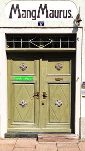 Eine grüne Tür eines Ladens mit einem Schild drauf. in der Unterkunft Maurushaus in Füssen