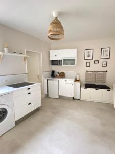 a kitchen with white cabinets and a washer and dryer at Appart'Hôtel -Le Bellifontain in Fontainebleau