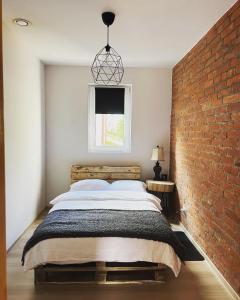 een slaapkamer met een groot bed en een bakstenen muur bij Pod Świerkami 