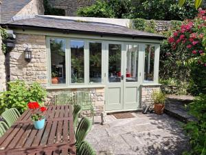 a small greenhouse with a wooden bench and flowers at Lovely property in the heart of Somerset, sleeps 9 in Shepton Mallet