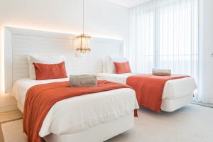 1 Schlafzimmer mit 2 Betten mit orangefarbener und weißer Bettwäsche in der Unterkunft Shantivillas Portimão in Portimão
