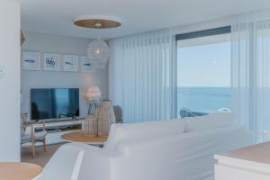 Sala de estar blanca con sofá blanco y TV en Shantivillas Portimão, en Portimão