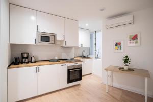 a kitchen with white cabinets and a table in it at Room Plaza España in Madrid