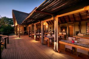 una gran terraza de madera con mesas y bancos en Bush Lodge – Amakhala Game Reserve, en Reserva de Amakhala