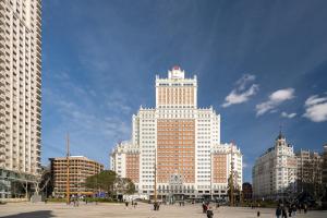 un edificio blanco alto con gente caminando delante de él en Room Plaza España, en Madrid