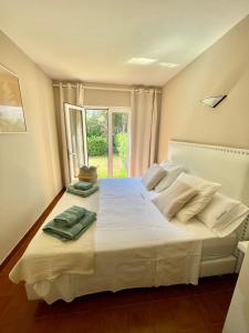 Schlafzimmer mit einem großen weißen Bett und einem Fenster in der Unterkunft Bonito apartamento con terraza, jardín y piscina in Cala'n Bosch