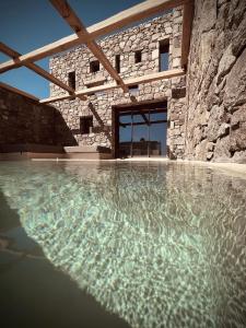 una piscina d'acqua di fronte a un edificio in pietra di Ria Mar Suites a Mykonos Città